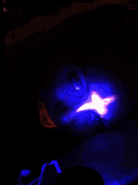 a person laying in the dark with a blue light on their face