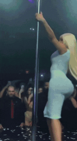 a woman in a white dress stands on a pole