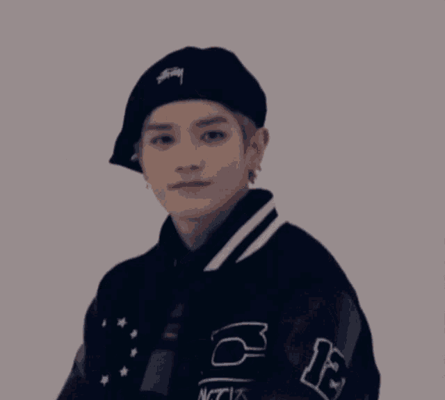 a young man wearing a black hat and a black jacket with the number 12 on the sleeve .