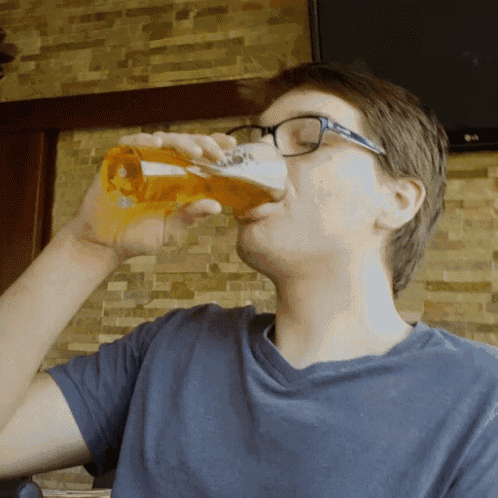 a man wearing glasses is drinking from a glass of beer