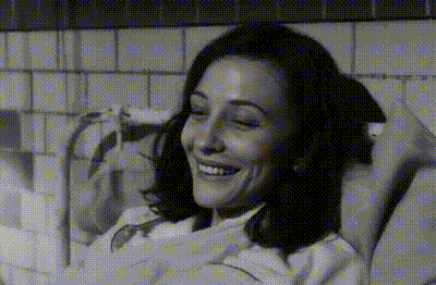 a black and white photo of a woman in a bathtub smiling
