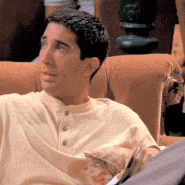 a man in a white shirt is sitting on a couch with a dog