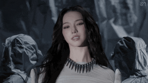 a woman wearing a white top and a black necklace with the letter s on it