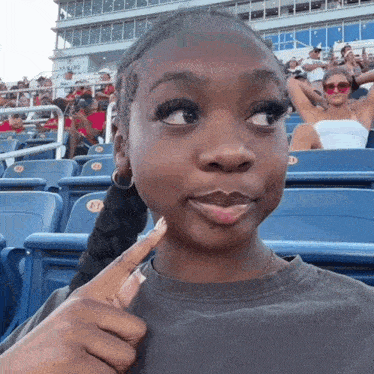 a girl sitting in a stadium with a delta logo on the back of the seat