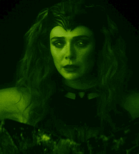 a close up of a woman 's face with a green light behind her