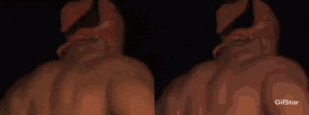 a couple of men are standing next to each other in a dark room . one of the men is wearing a hoodie .