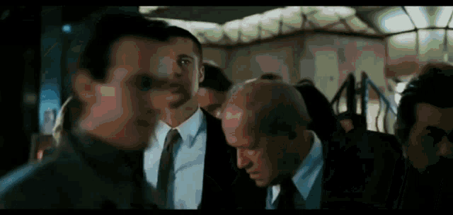 a group of men in suits and ties standing next to each other in a room .