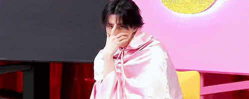 a man is covering his face with a pink blanket .