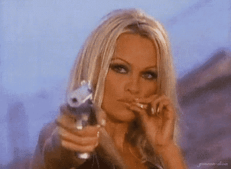 a woman with blonde hair is holding a gun in her hand and smoking a cigarette .