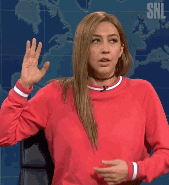 a woman in a red sweater waves her hand in front of a snl map