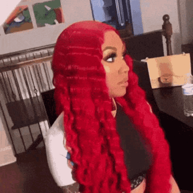 a woman with long red hair is sitting at a table in a room .