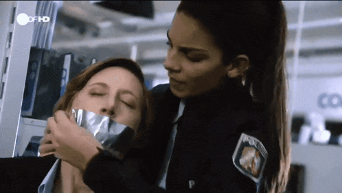 a woman is taped to another woman 's face by a police officer with a patch that says polizei