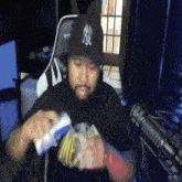 a man wearing a ny yankees hat is playing a video game .