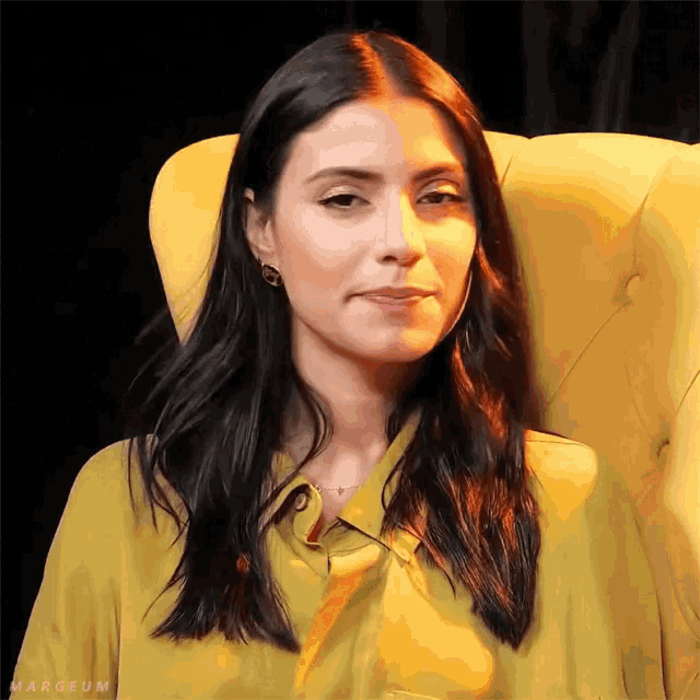 a woman in a yellow shirt is sitting in a yellow chair with the word margeum on the bottom right