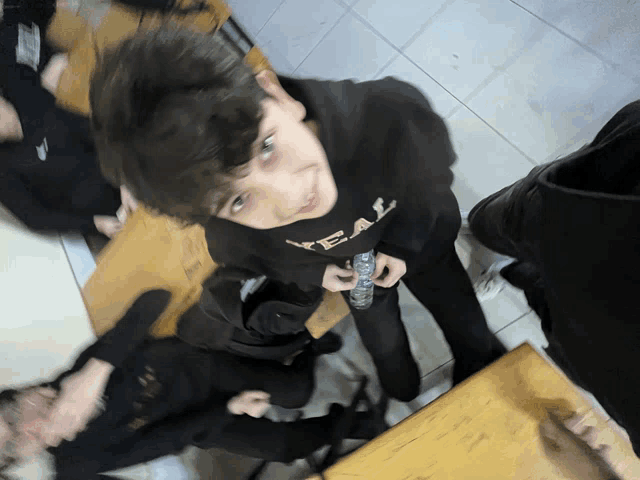 a boy wearing a black shirt that says yeal holds a remote control