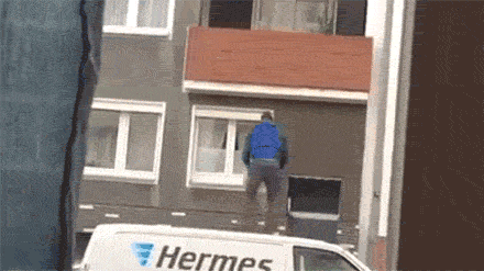 a man is climbing a building next to a white van that says hermes