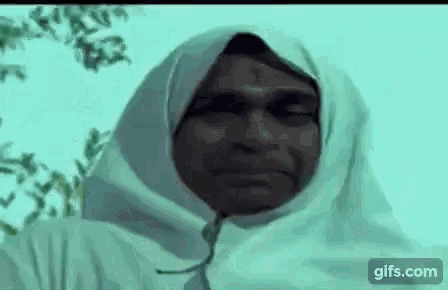 a man wearing a white scarf around his head is smiling .