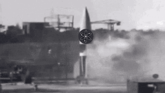 a black and white photo of a rocket being launched with an atom in the middle