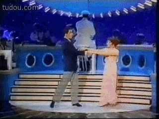 a man and woman are dancing on a stage and the website tudou.com is visible