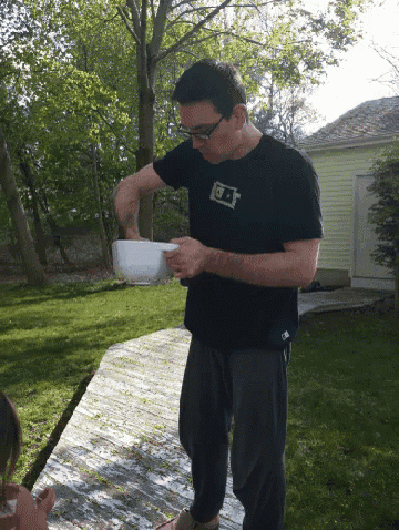 a man wearing a black shirt with the letter g on it is pouring something into a white bowl