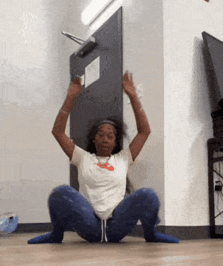 a woman squatting on the floor with her arms in the air