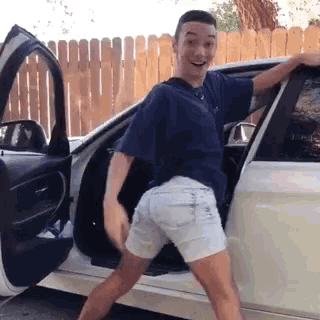 a young man in shorts is getting out of a car .