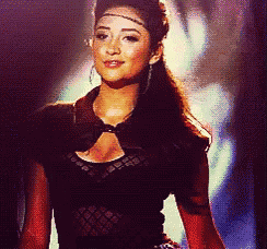 a woman wearing a black top and earrings is standing on a stage
