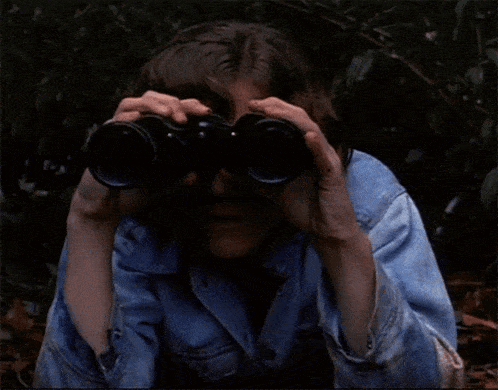 a young boy is looking through binoculars with a serious look on his face
