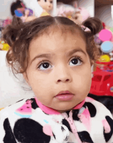 a little girl with pigtails is wearing a cow print pajamas