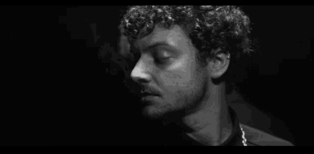 a black and white photo of a man with curly hair looking at another man .