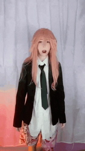 a girl with pink hair is wearing a suit and tie and making a funny face .