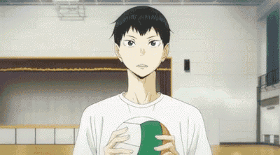a young man is holding a volleyball in his hands in a gym .