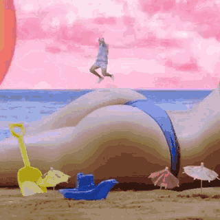 a woman in a bikini is laying on the beach with umbrellas and toys