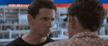 two men are looking at each other in a store and one of them is wearing a polka dot shirt .