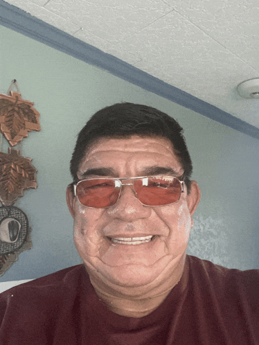 a man wearing red sunglasses and a red shirt smiles