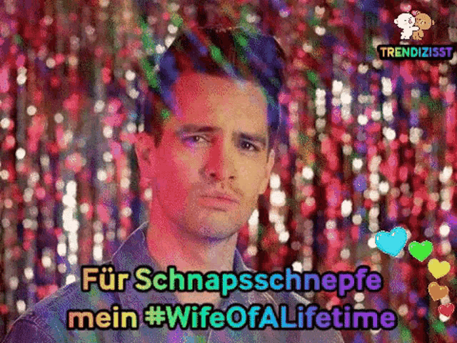 a man is standing in front of a colorful background with the words `` für schnappsschnepfe mein #wife of lifetime ''