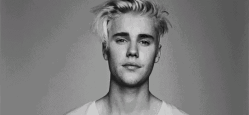 a black and white photo of a young man with blonde hair and a beard .