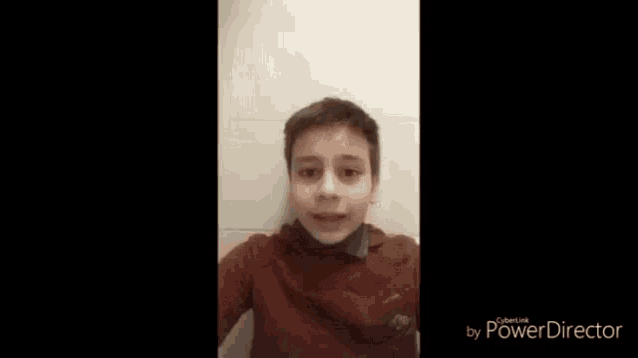 a young boy in a red shirt is sitting in a bathroom .