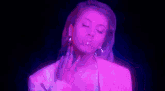 a woman is smoking a cigarette in a purple and blue light .