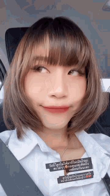 a woman with short hair is sitting in a car with a seat belt around her neck .