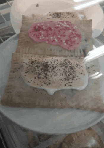 a toaster pastry with pink frosting and black sprinkles on it