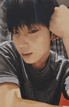 a young boy wearing a grey t-shirt with the word tokyo on the front