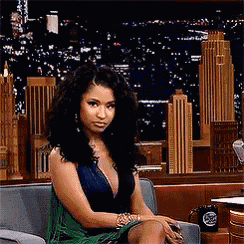 a woman in a green dress is sitting on a couch in front of a city skyline .