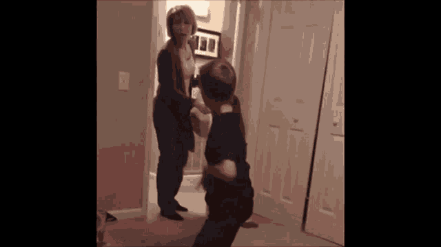 a woman is standing next to a boy in a room .