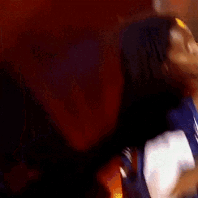 a man in a blue jacket is singing into a microphone while dancing on a stage .