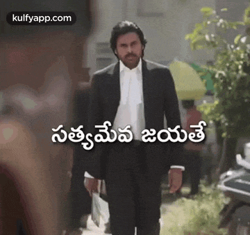 a man in a suit and tie is walking down a sidewalk in a foreign language .