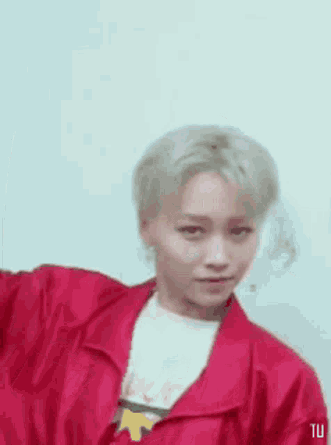 a young man in a red jacket and white shirt is making a funny face .