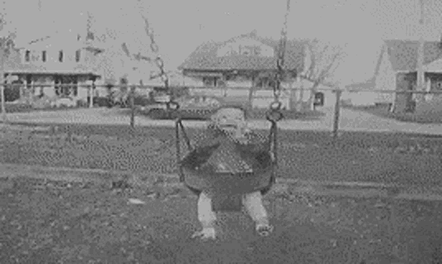 a child is sitting on a swing in a park .