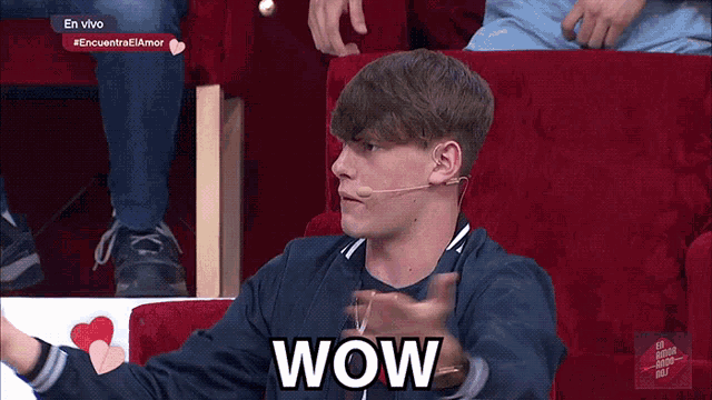 a young man sitting in a red chair with the word wow written on his face
