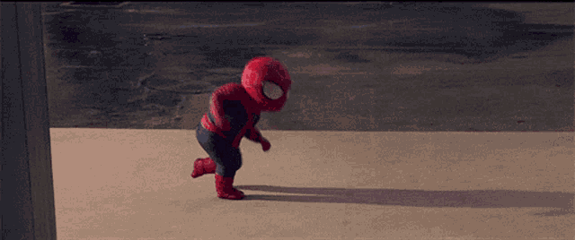 a baby dressed in a spiderman costume is running